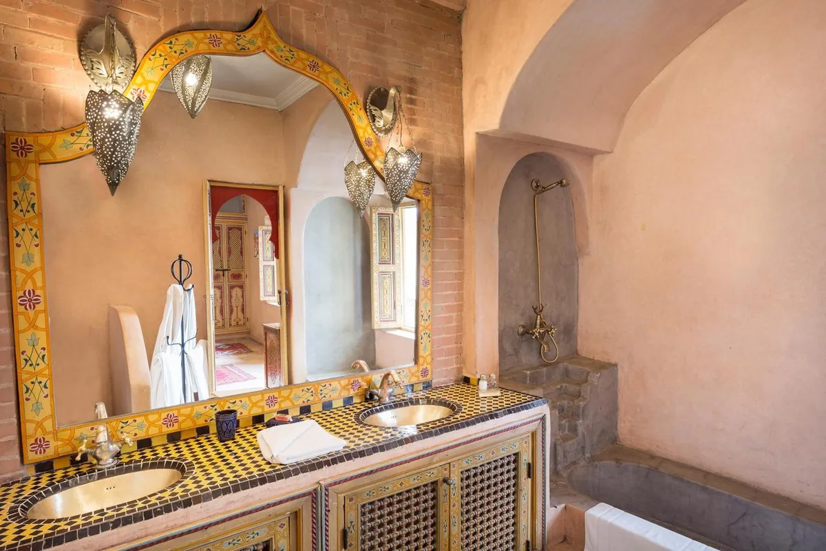 A gilded basin under an ornate mirror in a tadelakt bathroom