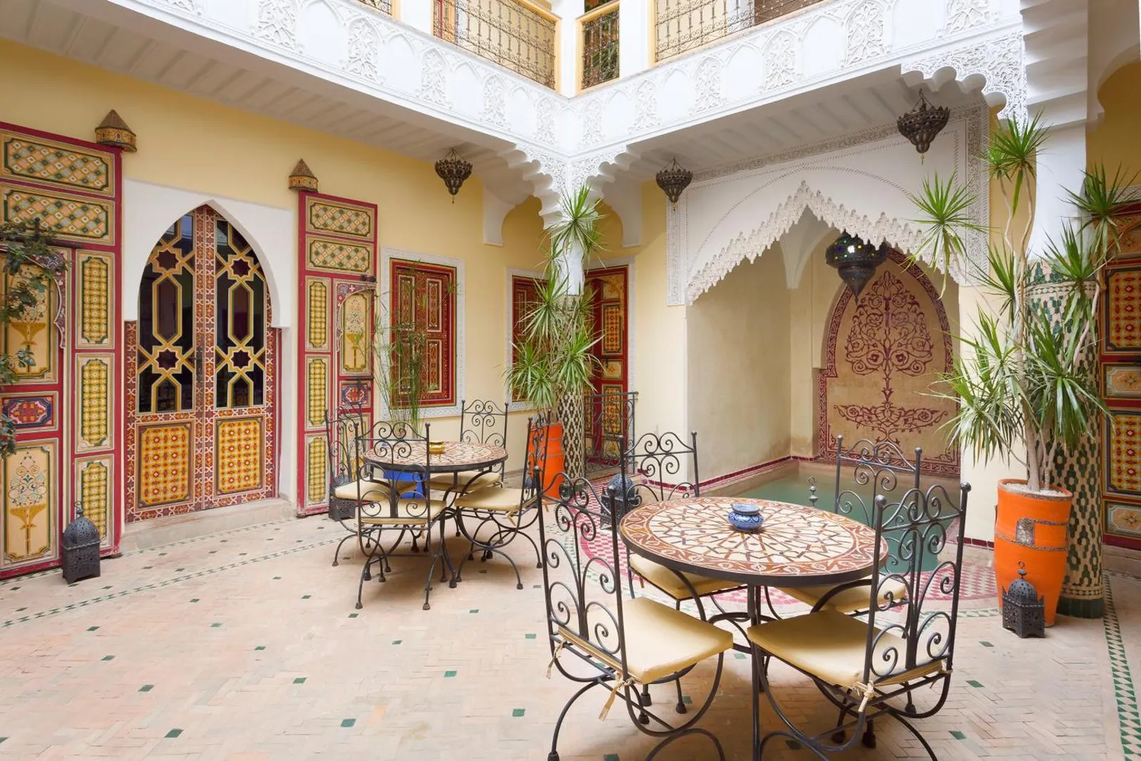 Mosaic tables set for breakfast under the courtyard arcades