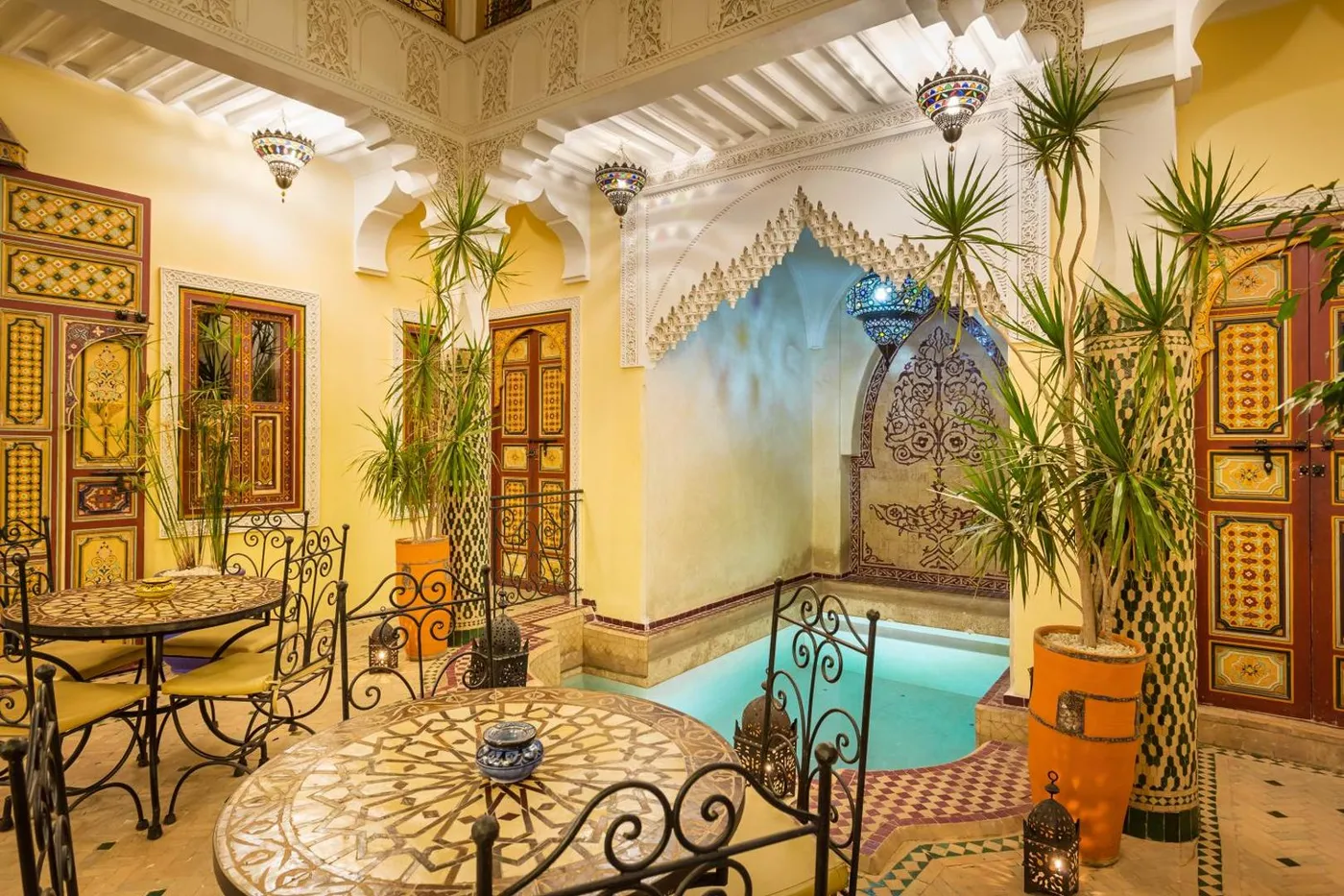 The teal plunge pool against a painted courtyard wall