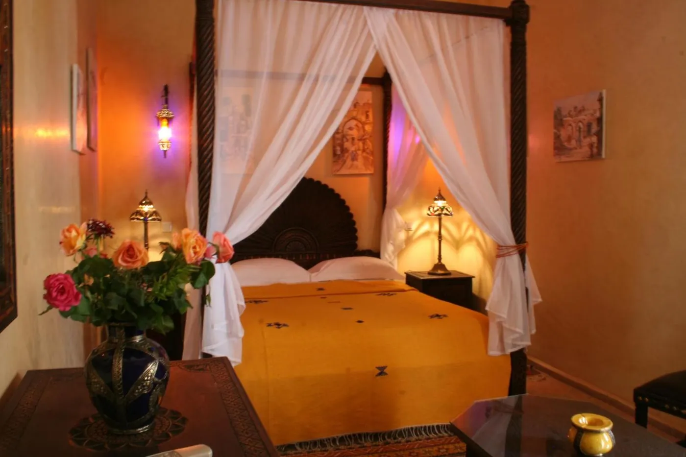 A canopy bed with flowers on the side table