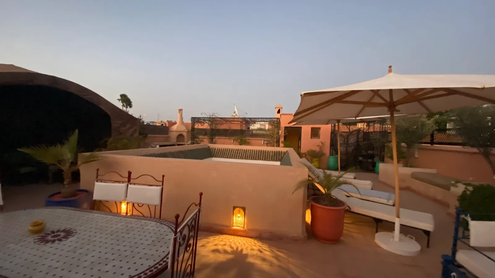 The rooftop terrace of Riad Sofia at dusk, medina rooftops beyond